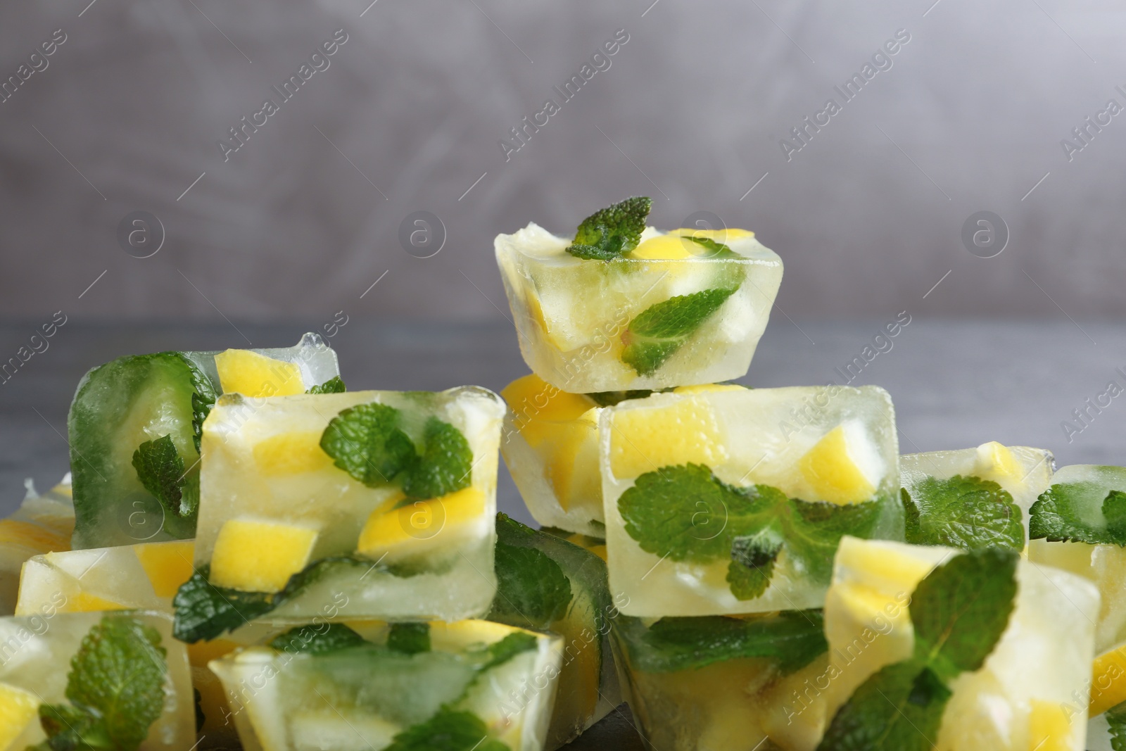 Photo of Ice cubes with mint and lemon on grey background, closeup