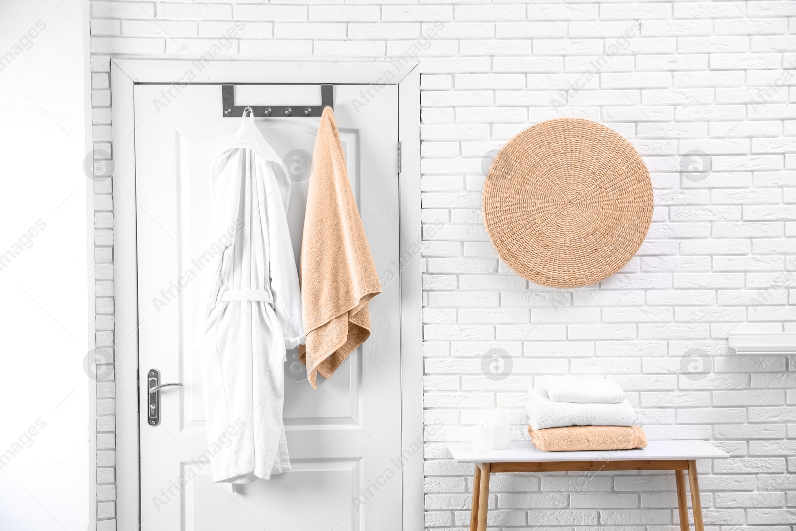 Photo of Soft comfortable bathrobe and towel hanging on door in stylish room interior