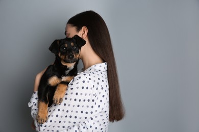 Young woman with cute puppy on light grey background. Space for text
