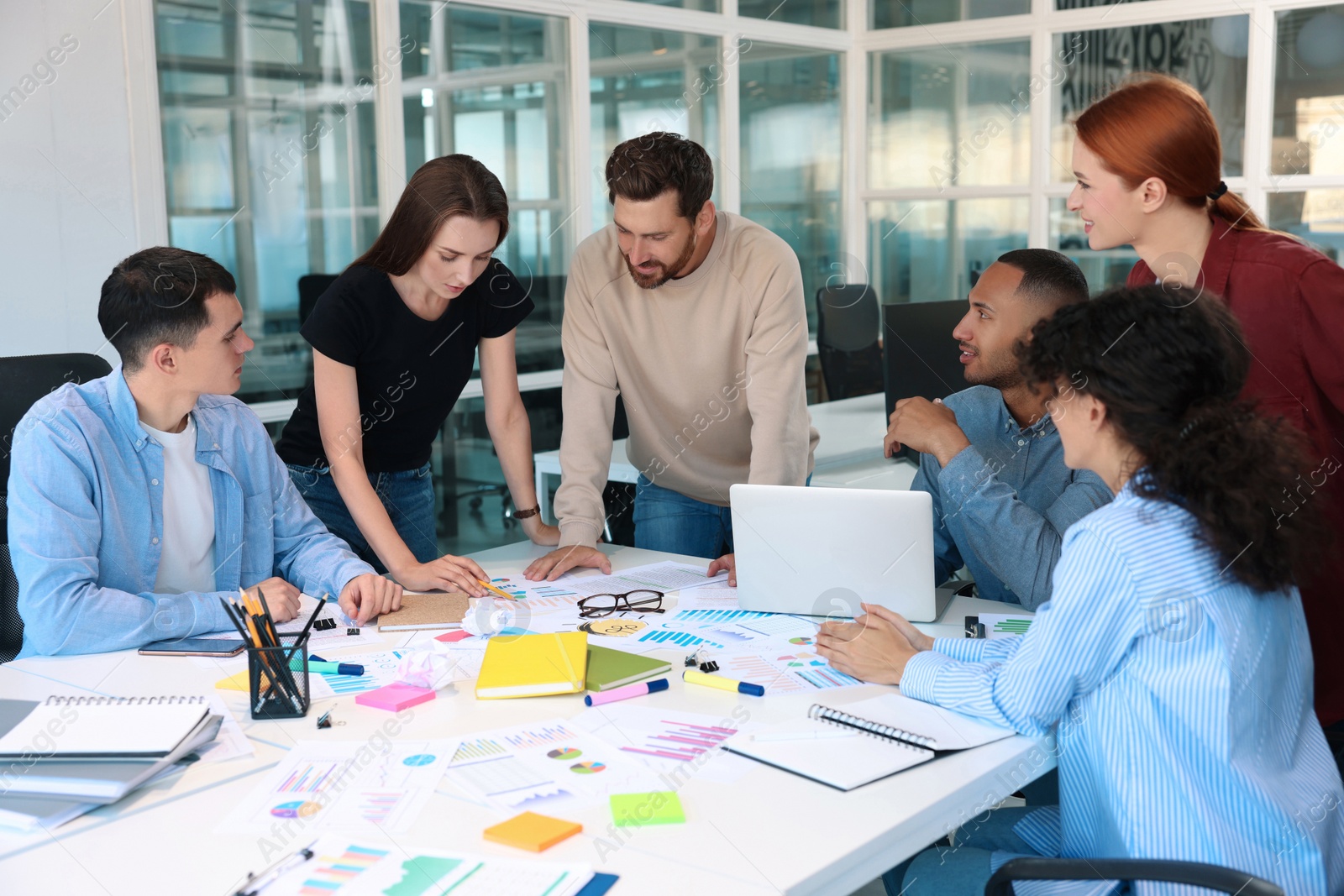 Photo of Team of employees working together at table in office. Startup project