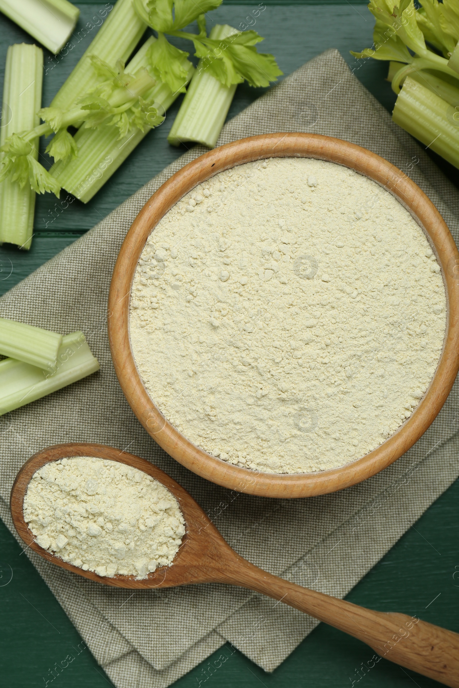 Photo of Natural celery powder and fresh stalks on green wooden table, flat lay