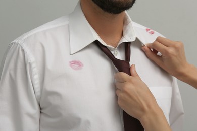 Woman noticed lipstick kiss marks while straightening her husband's shirt and necktie, closeup