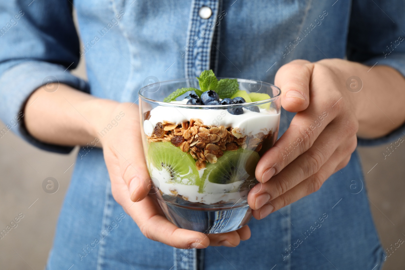 Photo of Woman holding glass of tasty homemade granola dessert, closeup. Healthy breakfast