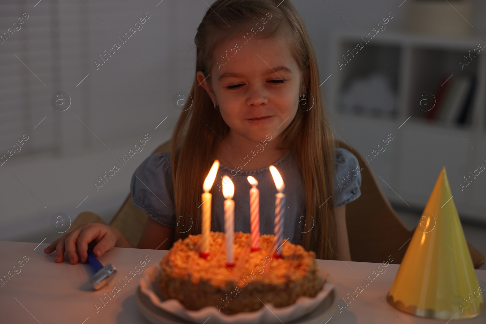 Photo of Cute girl with birthday cake at table indoors