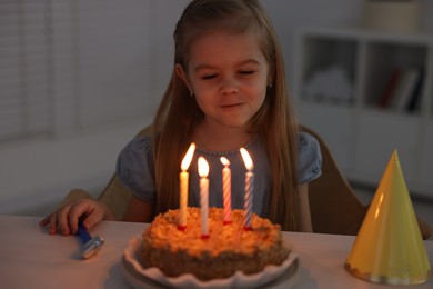 Cute girl with birthday cake at table indoors