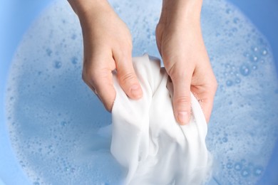 Photo of Top view of woman hand washing white clothing in suds, closeup