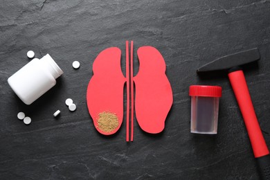 Flat lay composition of kidneys paper cutout with sand on black background