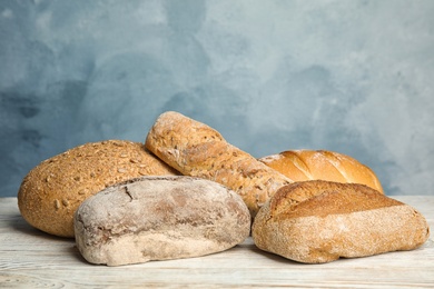 Loaves of different breads on white wooden table