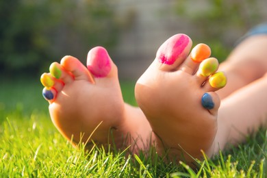 Photo of Teenage girl with painted toes on green grass outdoors, closeup