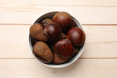 Sweet fresh edible chestnuts on light wooden table, top view