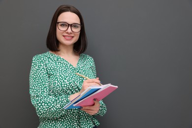 Photo of Happy young intern with notebooks and pen on grey background. Space for text