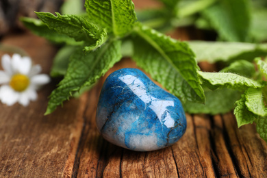 Beautiful blue shattuckite stone and fresh healing herbs on wooden table