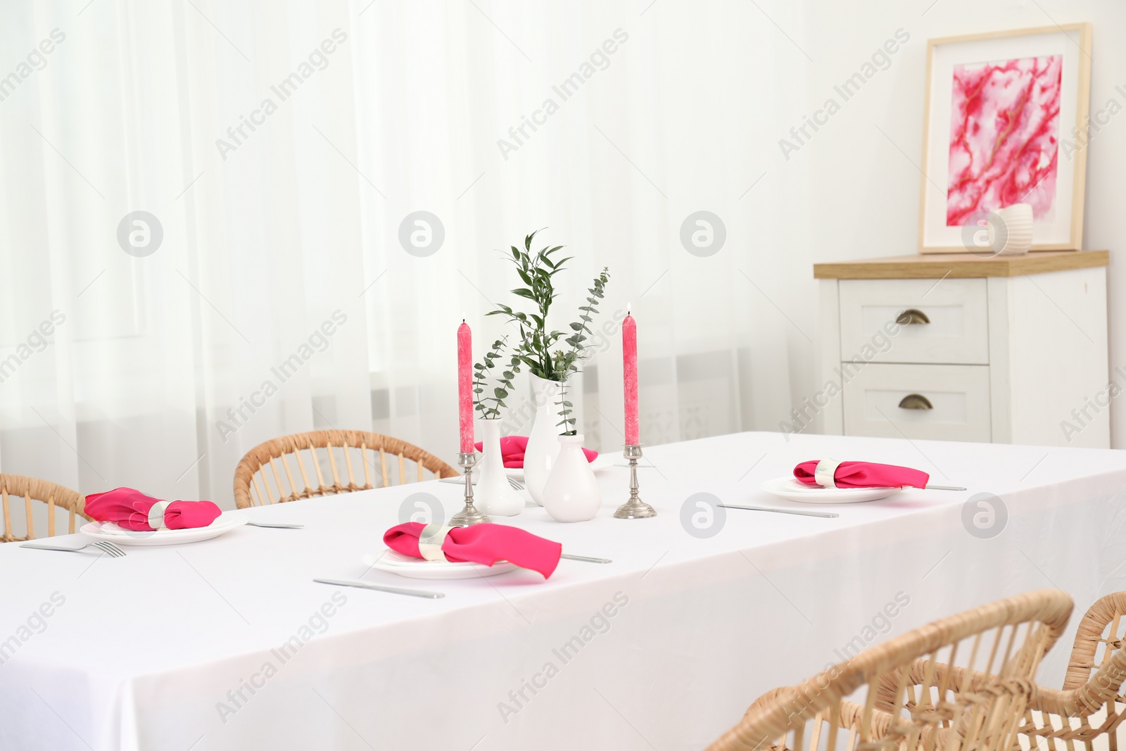 Photo of Beautiful table setting with green branches in vases and burning candles in dining room