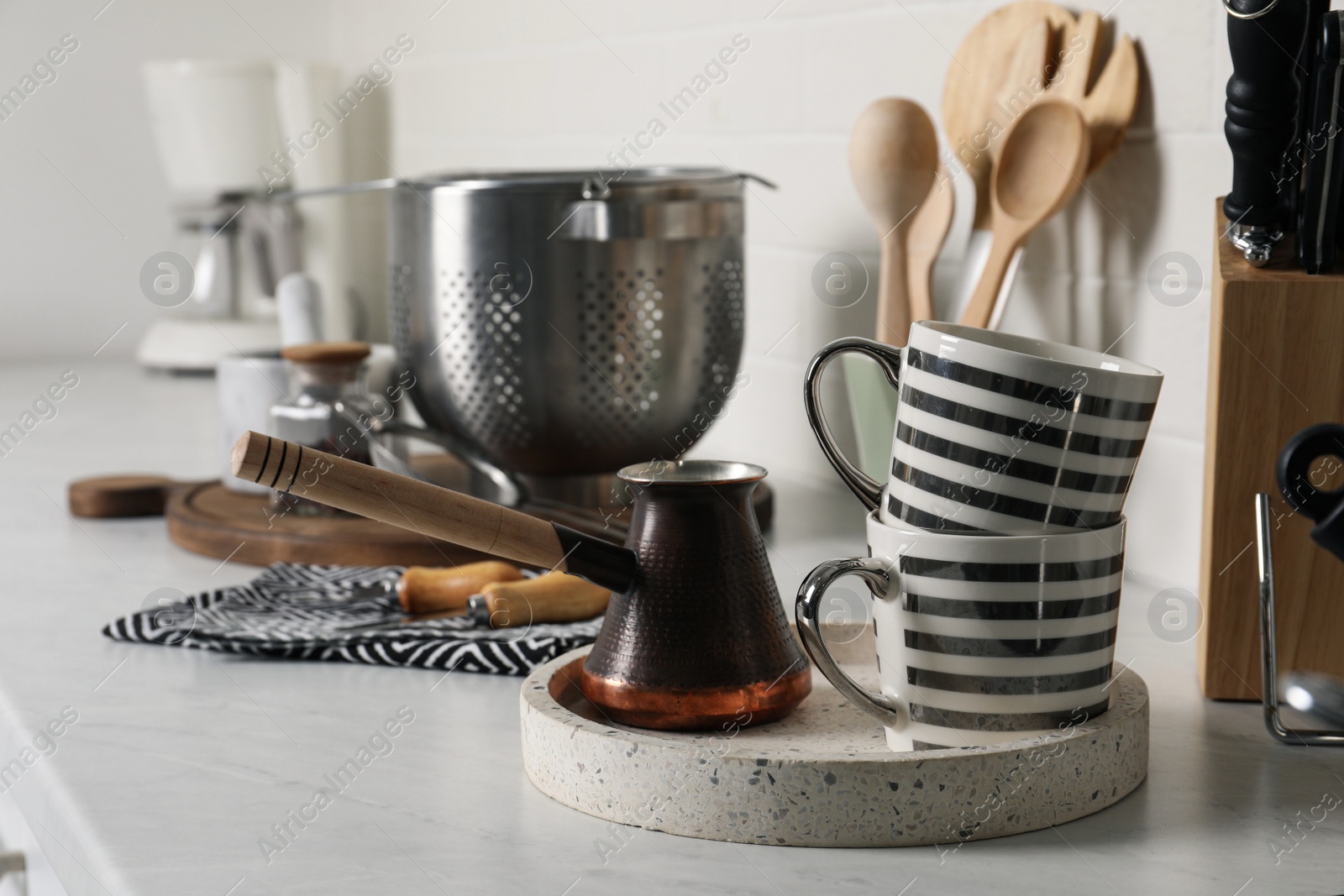 Photo of Cezve, cups and other cooking utensils on countertop in kitchen