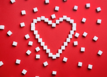 Photo of Heart shape made of refined sugar cubes on color background, top view
