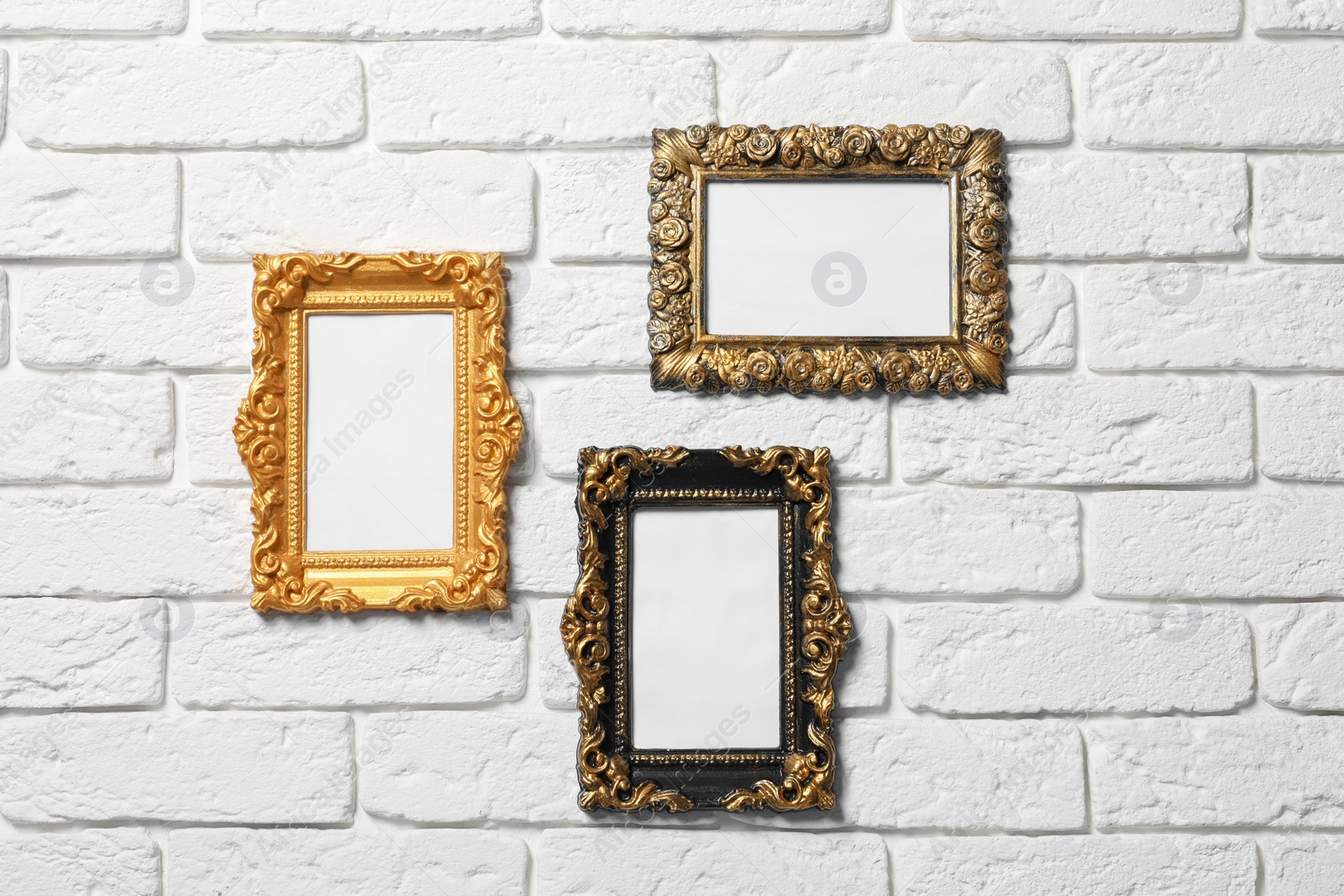 Photo of Blank vintage frames hanging on white brick wall. Mockup for design