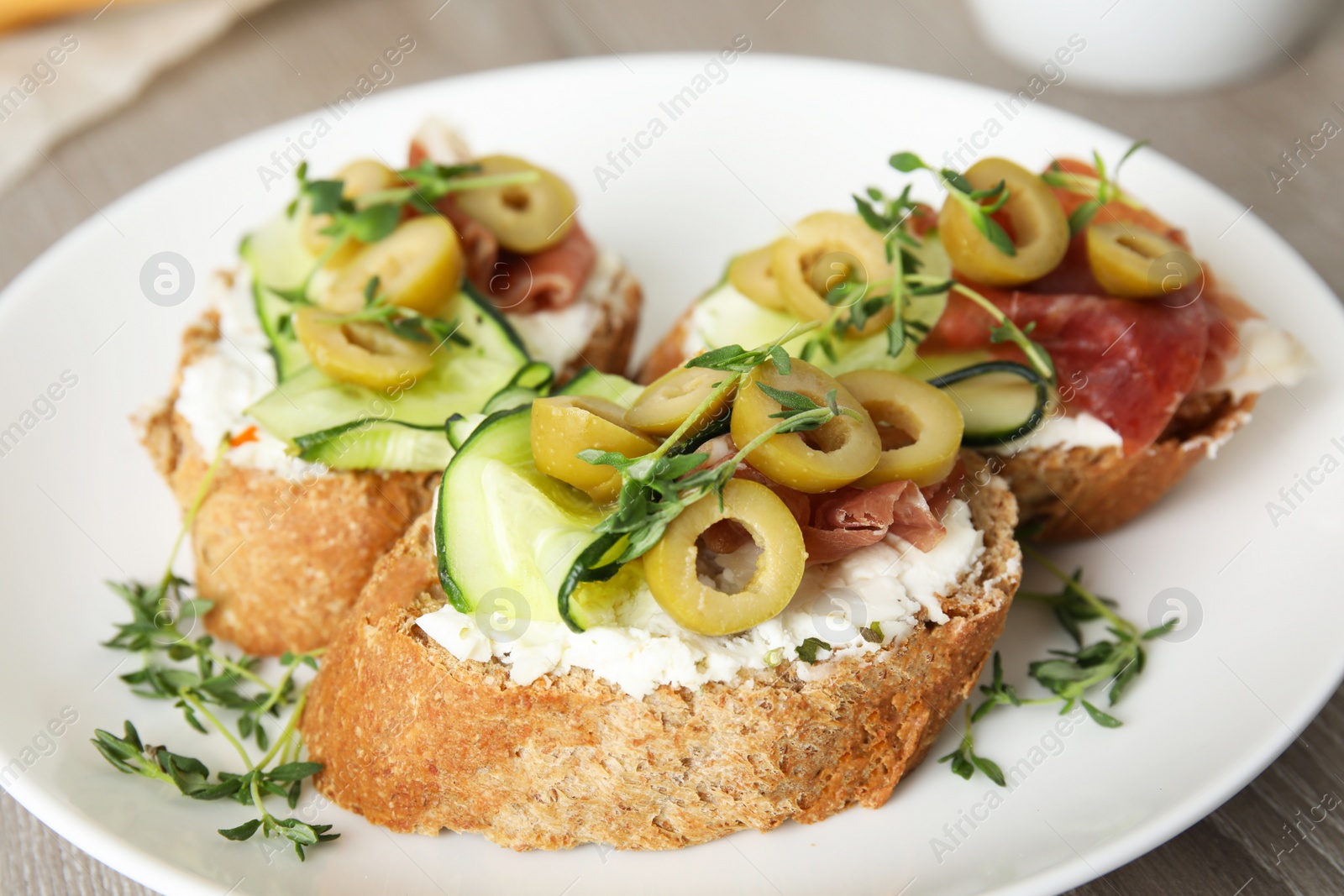 Photo of Plate of delicious bruschettas with prosciutto on table, closeup