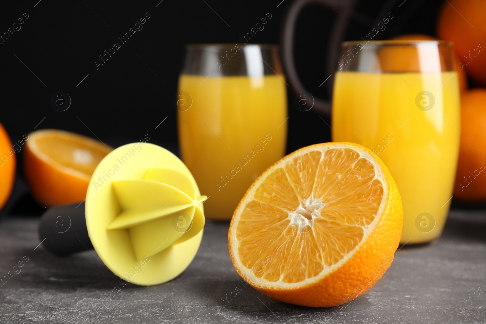 Photo of Cut fresh ripe orange, reamer and juice on grey table, closeup