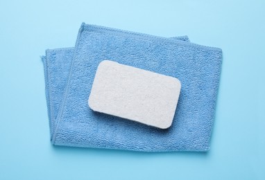 Photo of Sponge and rag on light blue background, top view