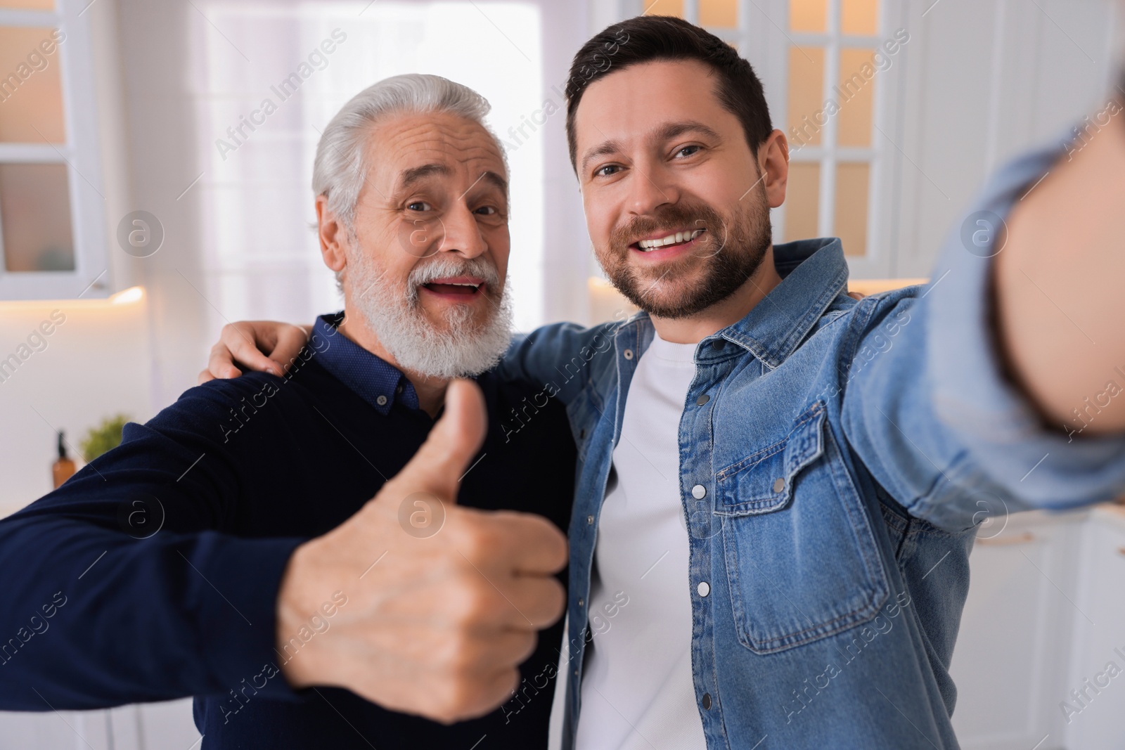 Photo of Happy son and his dad taking selfie at home