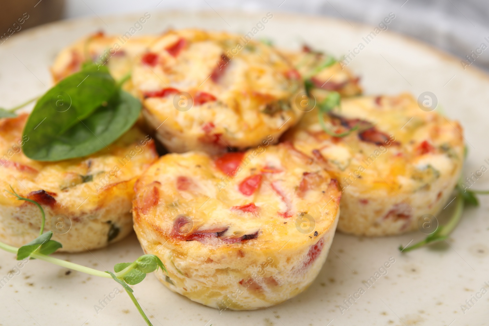 Photo of Freshly baked bacon and egg muffins with cheese on plate, closeup