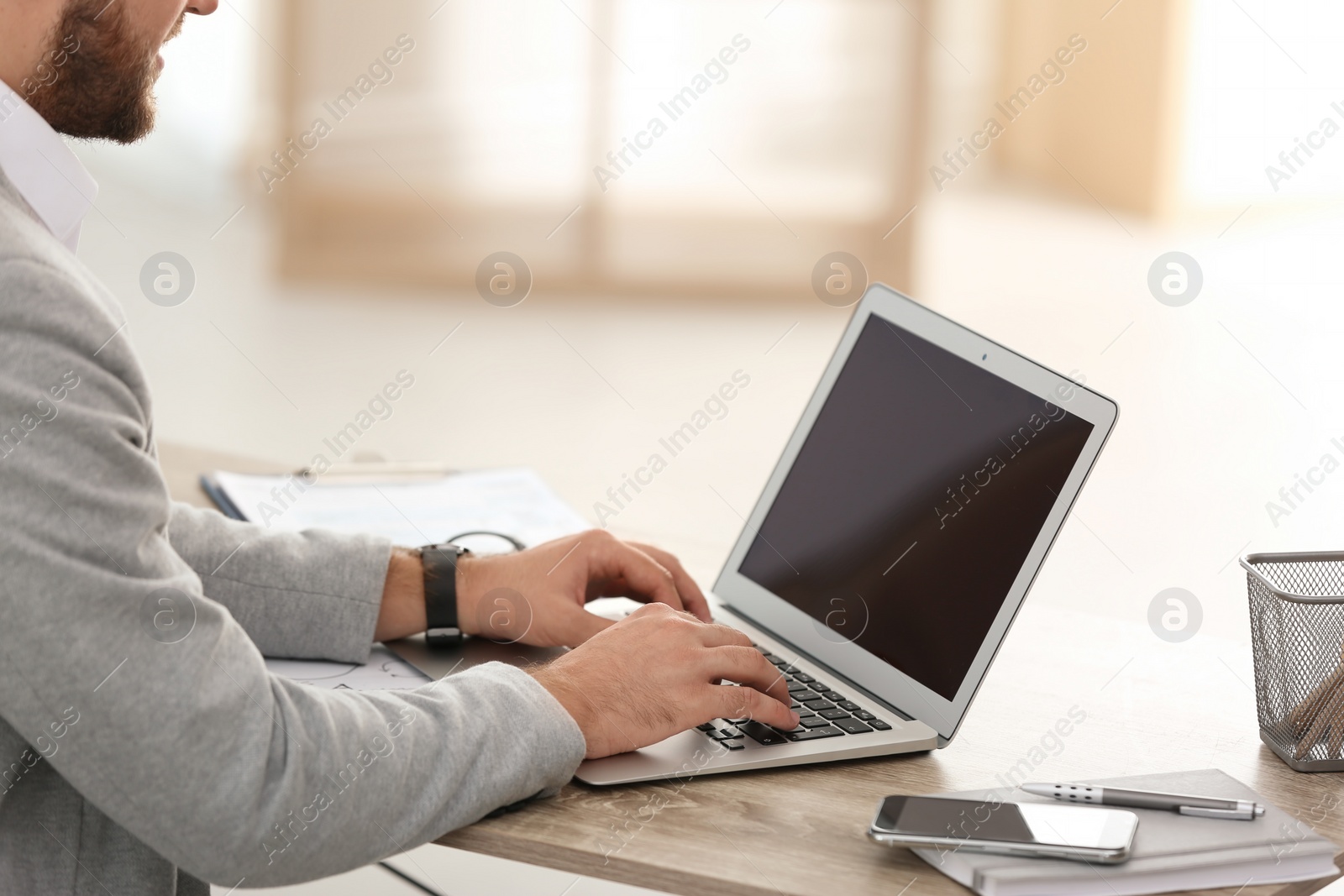 Photo of Young businessman using laptop at table in office