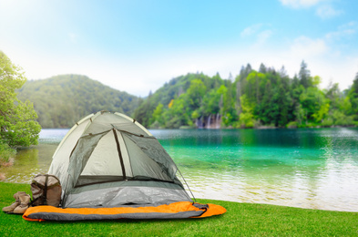 Image of Camping tent with sleeping bag and boots near beautiful river