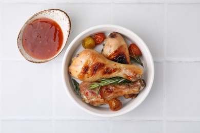 Marinade, roasted chicken drumsticks, rosemary and tomatoes on white tiled table, flat lay