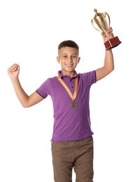 Happy boy with golden winning cup and medal on white background
