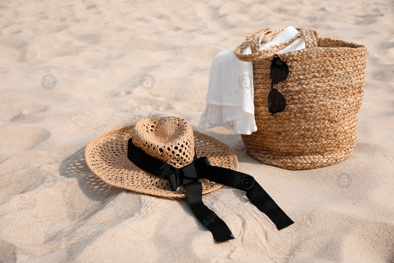 Photo of Beach bag, towel, sunglasses and hat on sand, space for text