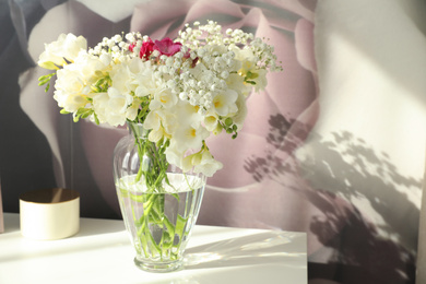 Beautiful bouquet with fresh freesia flowers in vase on table indoors. Space for text