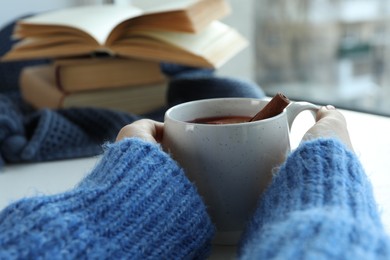 Photo of Woman holding cup of mulled wine near window indoors, closeup. Winter drink