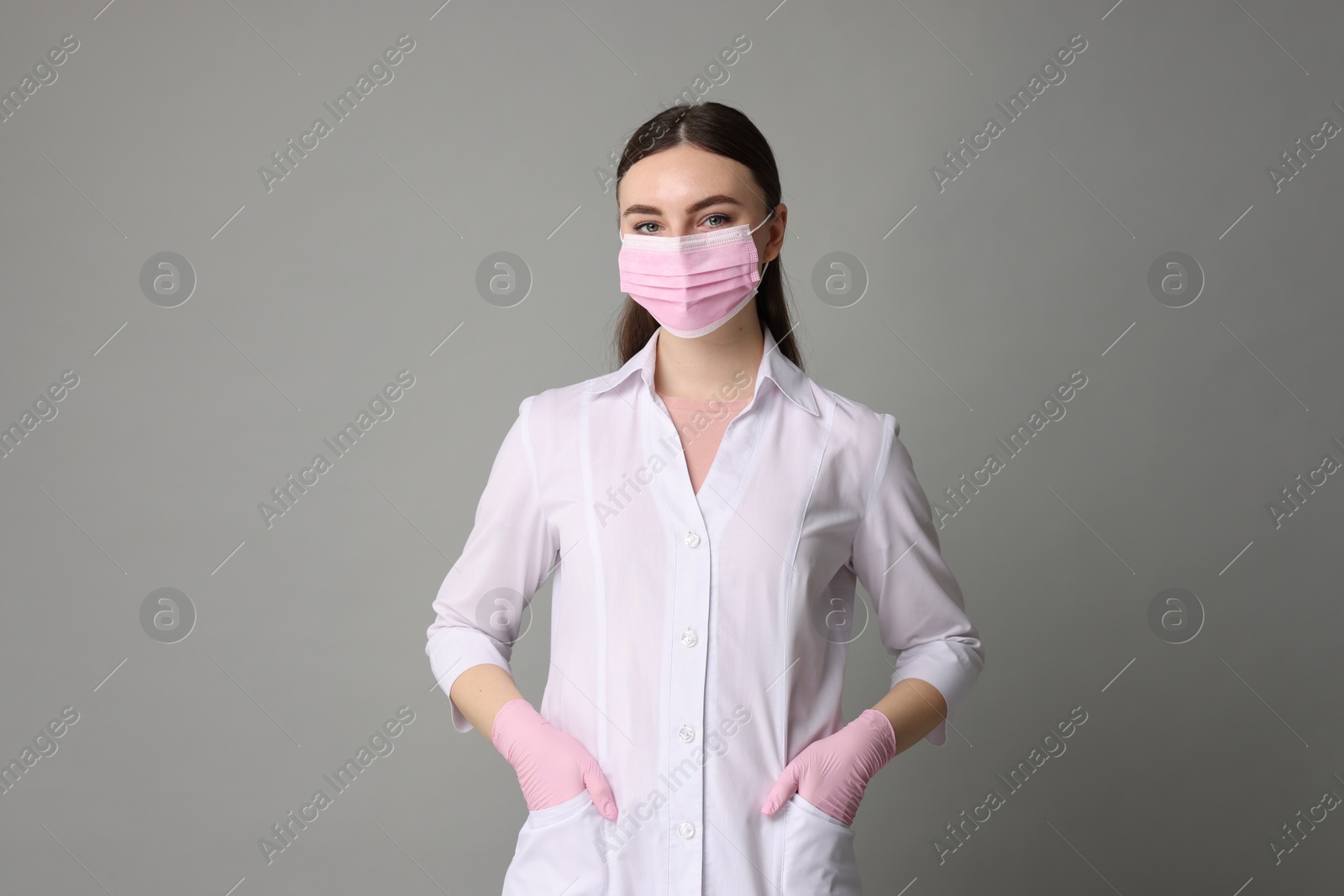 Photo of Cosmetologist in medical uniform on grey background