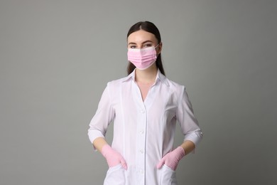 Photo of Cosmetologist in medical uniform on grey background