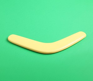 Yellow wooden boomerang on green background. Outdoor activity