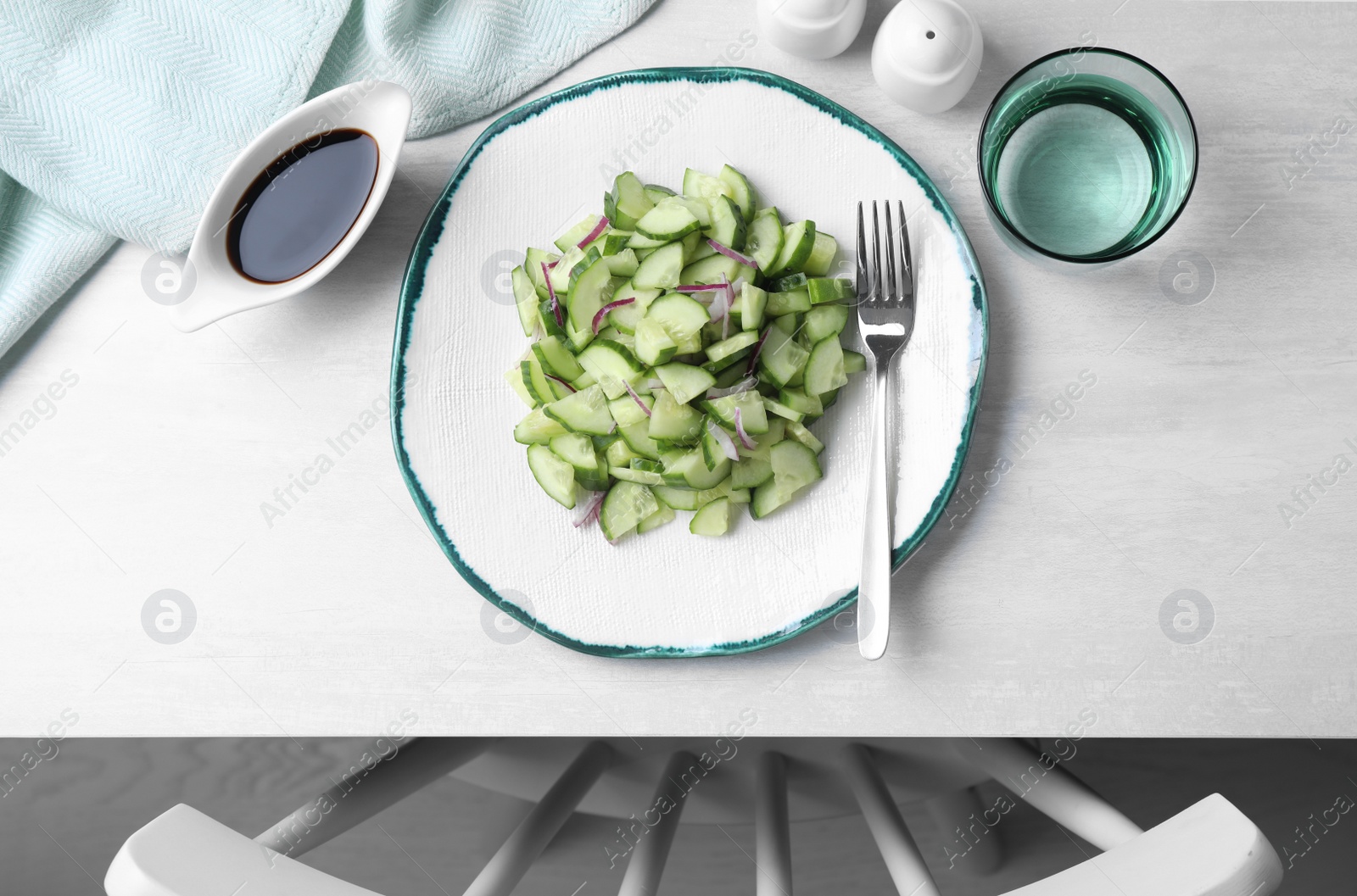 Photo of Plate of vegetarian salad with cucumber and onion served on table, top view