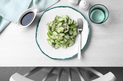 Plate of vegetarian salad with cucumber and onion served on table, top view