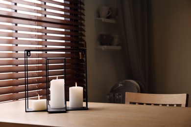 Wooden dining table with candles in room. Interior design