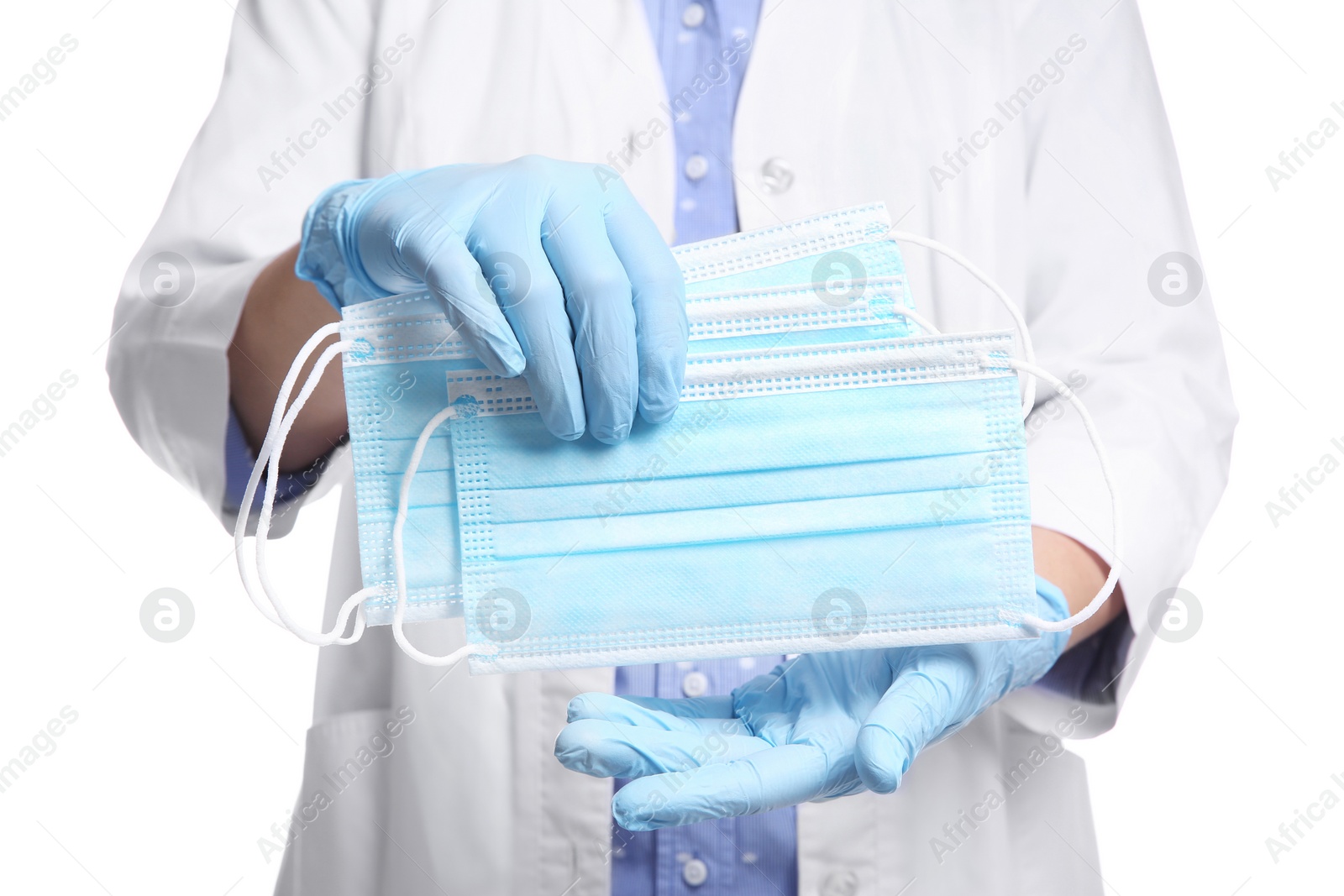 Photo of Doctor in latex gloves holding disposable face masks on white background, closeup. Protective measures during coronavirus quarantine