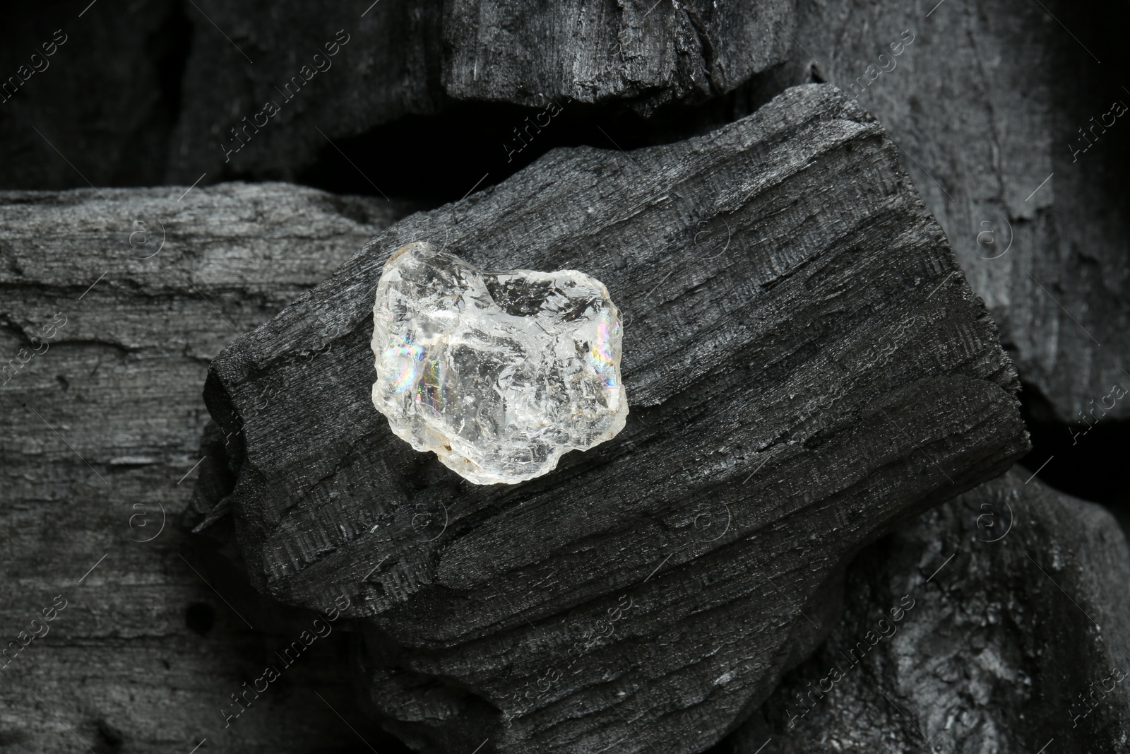 Photo of Beautiful shiny diamond on coal, top view