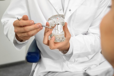 Photo of Professional dentist showing patient jaws model in clinic, closeup