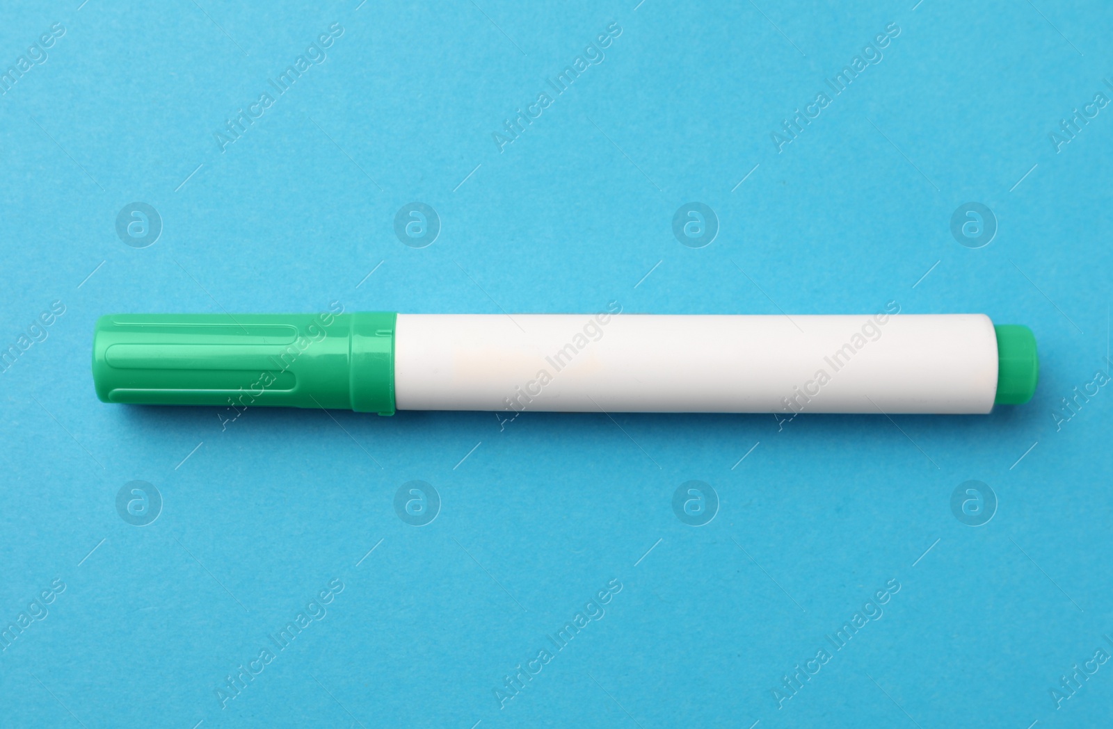 Photo of Bright green marker on light blue background, top view