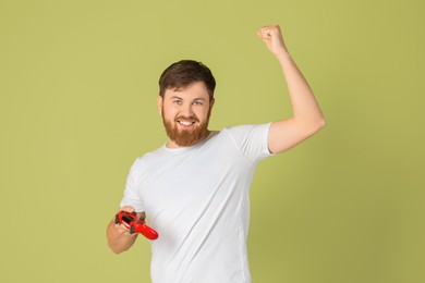 Happy man with game controller on pale green background