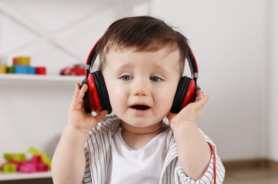 Cute little boy in headphones listening to music at home