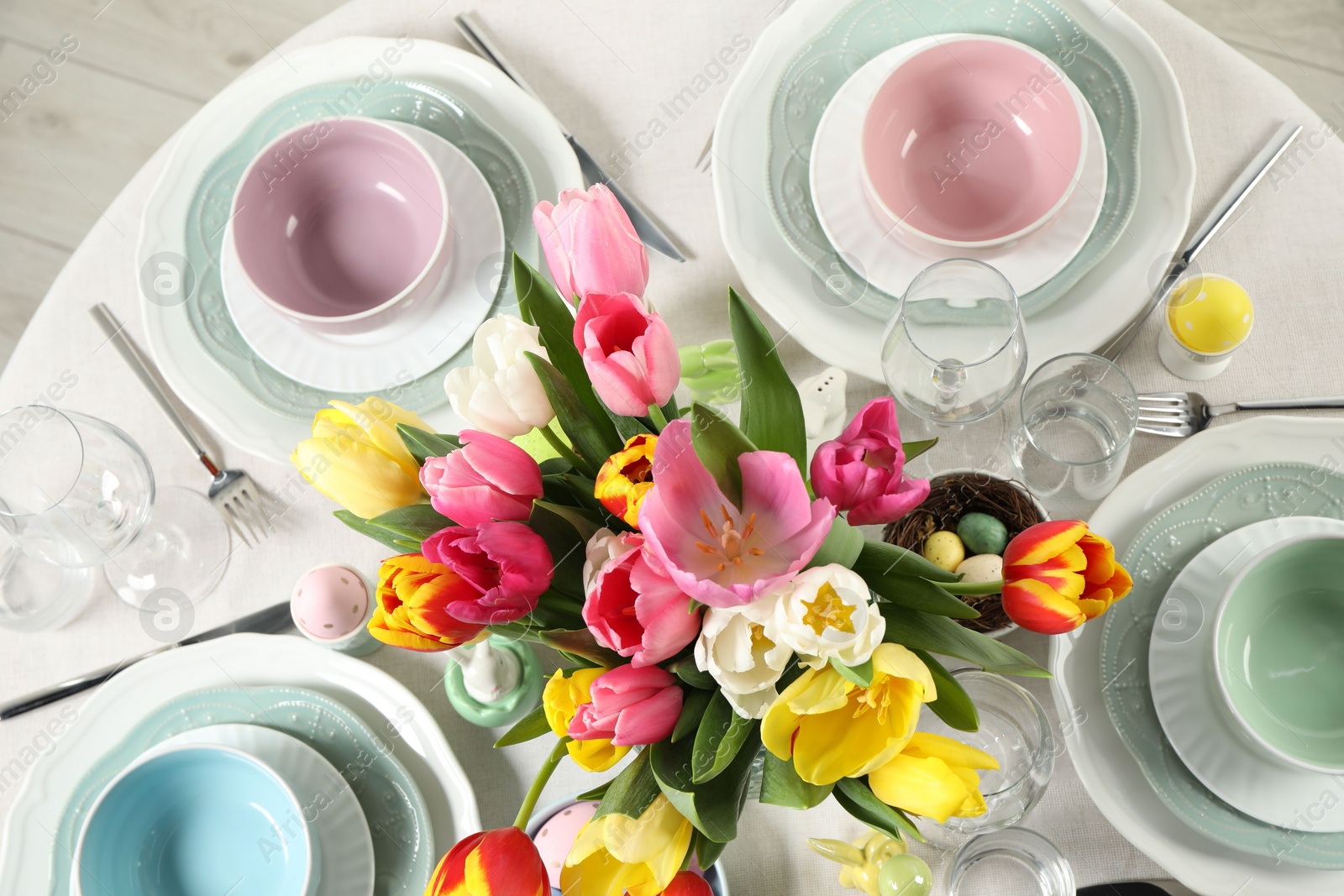 Photo of Festive Easter table setting with beautiful flowers and painted eggs, top view