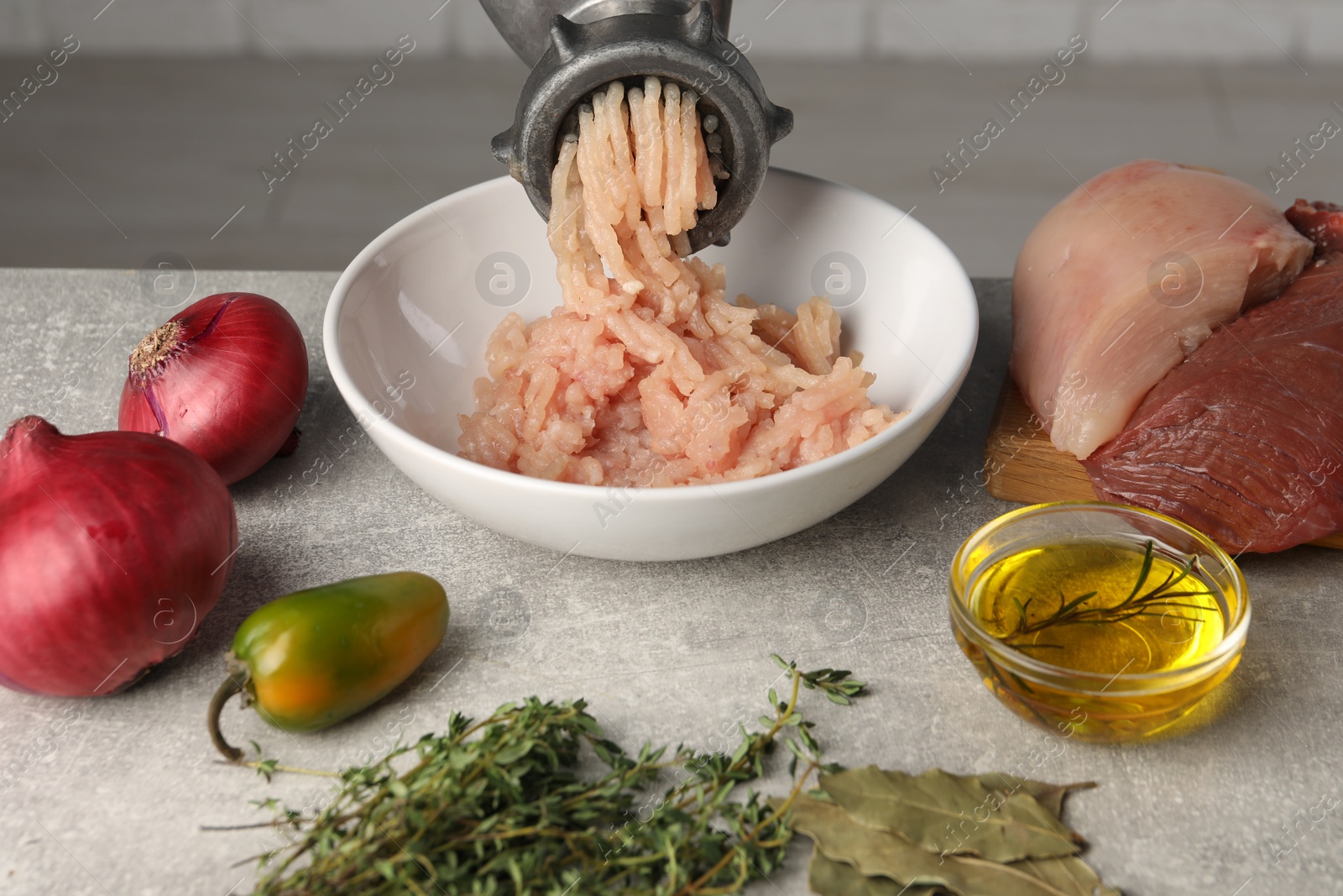 Photo of Metal meat grinder with chicken mince and different products on light grey table