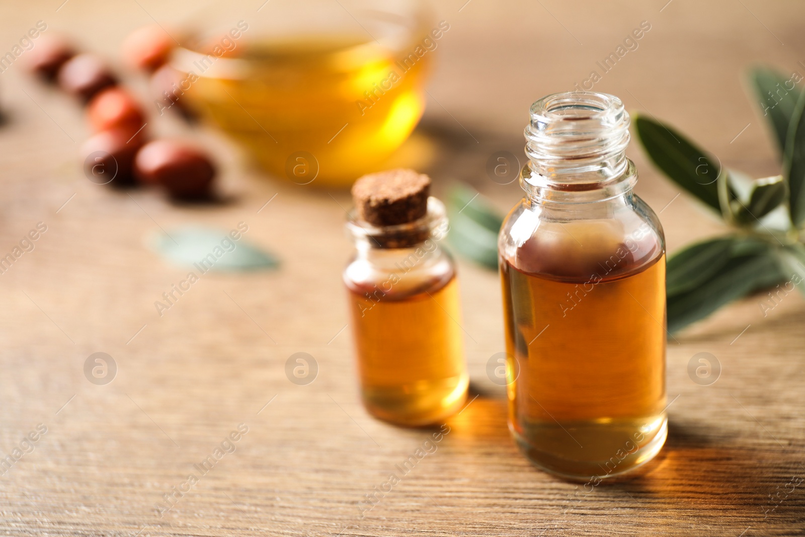 Photo of Glass bottles with jojoba oil on wooden table. Space for text