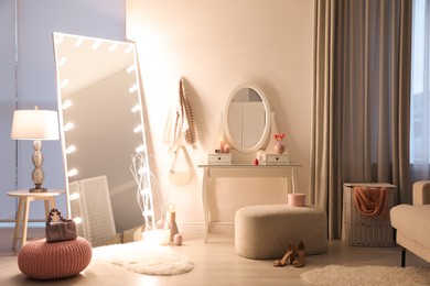 Photo of Large mirror with light bulbs and dressing table in stylish room. Interior design