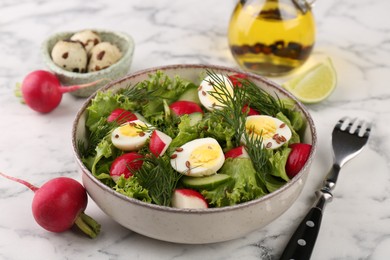 Delicious salad with radish, lettuce and boiled quail eggs served on white marble table, closeup