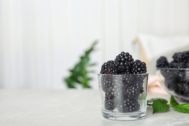 Photo of Glass with fresh blackberry on table against blurred background